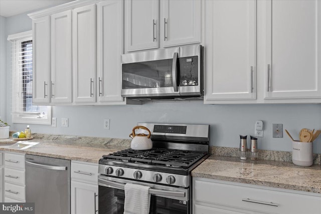 kitchen featuring light stone counters, white cabinets, and stainless steel appliances