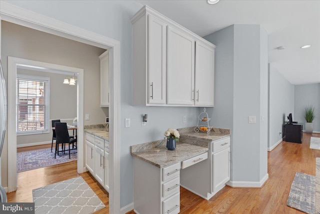 kitchen featuring baseboards, white cabinetry, and light wood finished floors