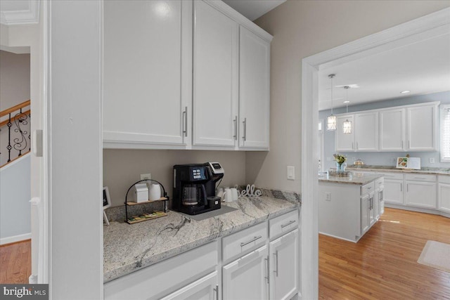 kitchen with light stone counters, light wood-style flooring, and white cabinets