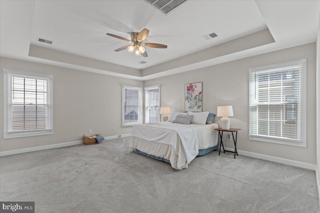 carpeted bedroom featuring visible vents, a raised ceiling, and baseboards