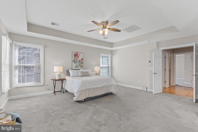 bedroom with a tray ceiling, carpet flooring, and visible vents