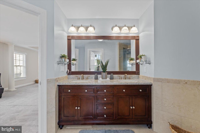 bathroom with double vanity, an enclosed shower, tile walls, and a sink