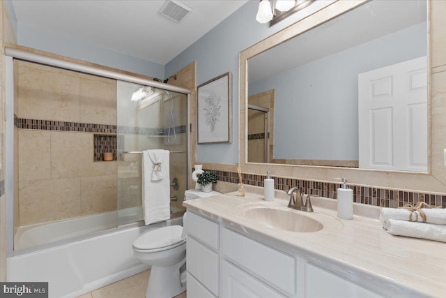 full bathroom with tasteful backsplash, visible vents, bath / shower combo with glass door, toilet, and vanity