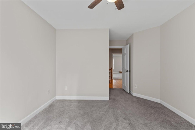 carpeted empty room featuring baseboards and a ceiling fan