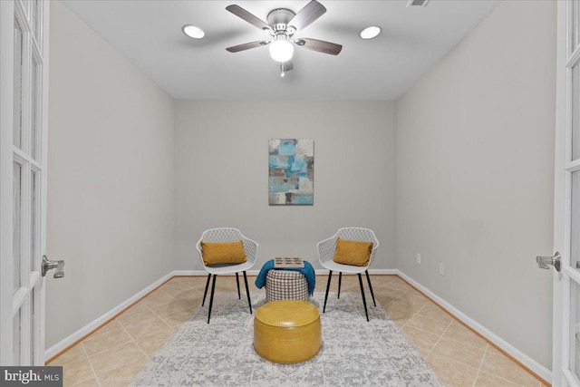 living area featuring light tile patterned floors, visible vents, baseboards, and a ceiling fan