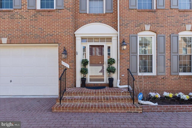 view of exterior entry featuring brick siding and decorative driveway