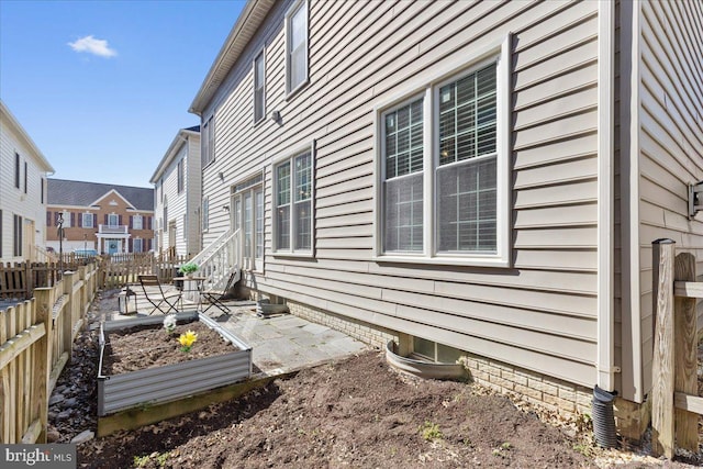 view of property exterior featuring a patio, a vegetable garden, and fence