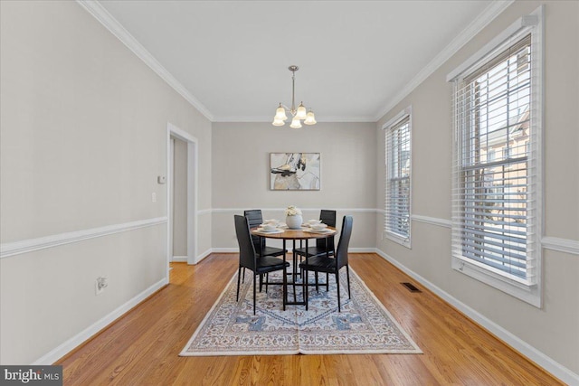 dining area featuring light wood-type flooring, baseboards, an inviting chandelier, and crown molding