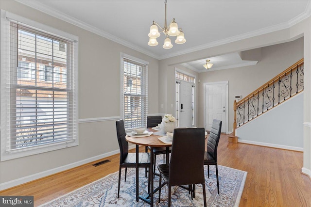 dining area featuring visible vents, baseboards, stairway, an inviting chandelier, and wood finished floors