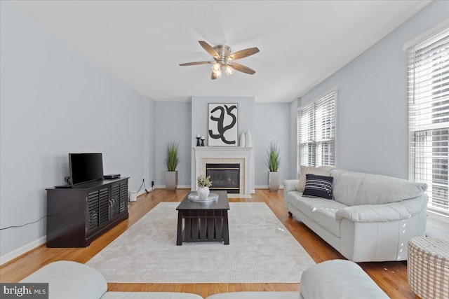 living area featuring ceiling fan, baseboards, wood finished floors, and a fireplace with flush hearth