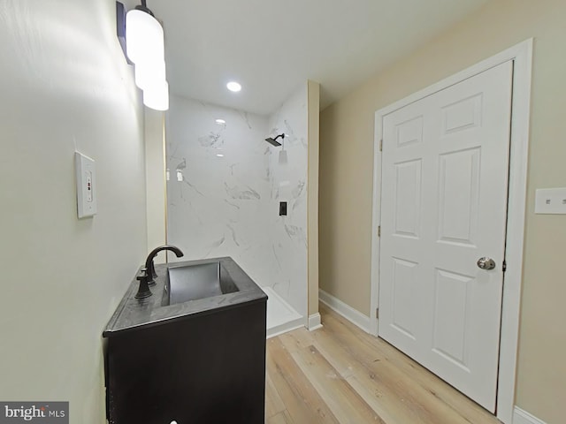 bathroom with wood-type flooring, sink, and a tile shower