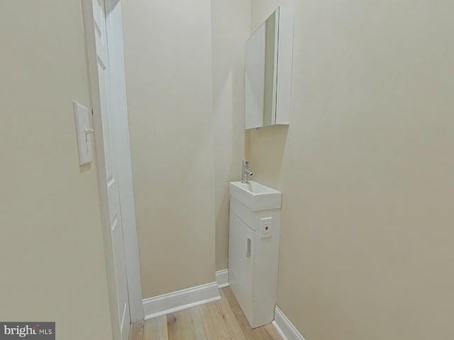 clothes washing area with sink and light hardwood / wood-style flooring