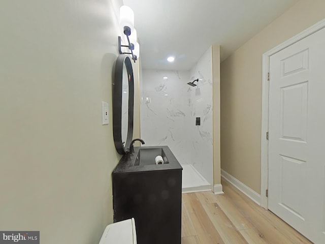 bathroom with hardwood / wood-style flooring, vanity, and a tile shower