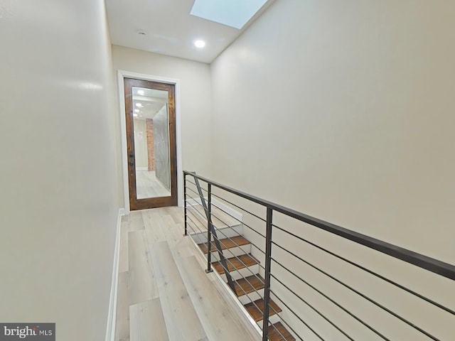 hallway featuring a skylight and light wood-type flooring