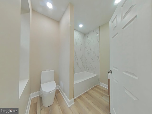 bathroom featuring tiled shower / bath, hardwood / wood-style flooring, and toilet