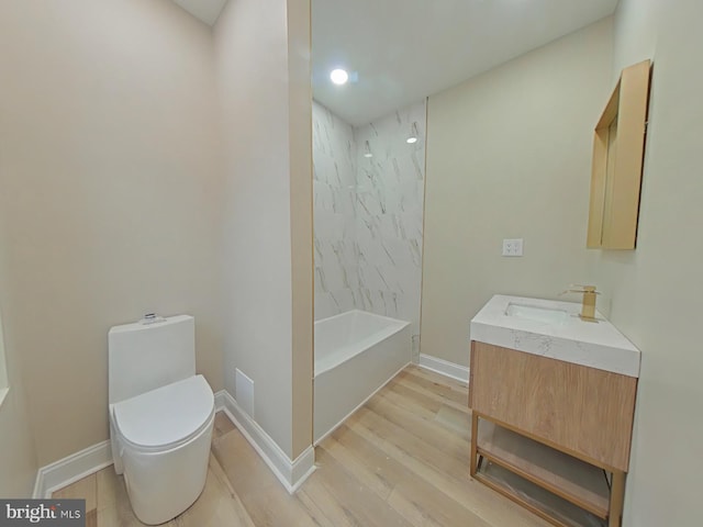 full bathroom featuring vanity, wood-type flooring, tiled shower / bath, and toilet