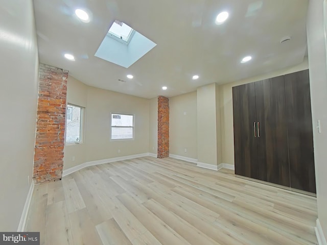 empty room with a skylight and light wood-type flooring