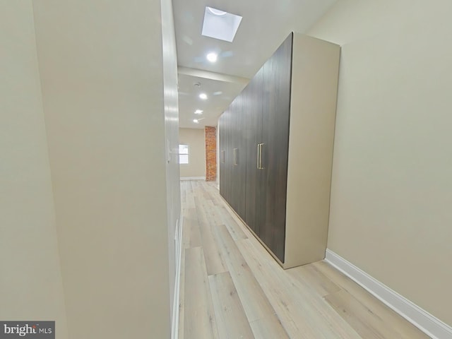 corridor featuring a skylight and light wood-type flooring