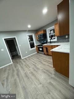 217 S 4th St, Vineland, NJ 08360 - kitchen featuring light wood-type flooring, baseboards, gas stove, brown cabinetry, and light countertops