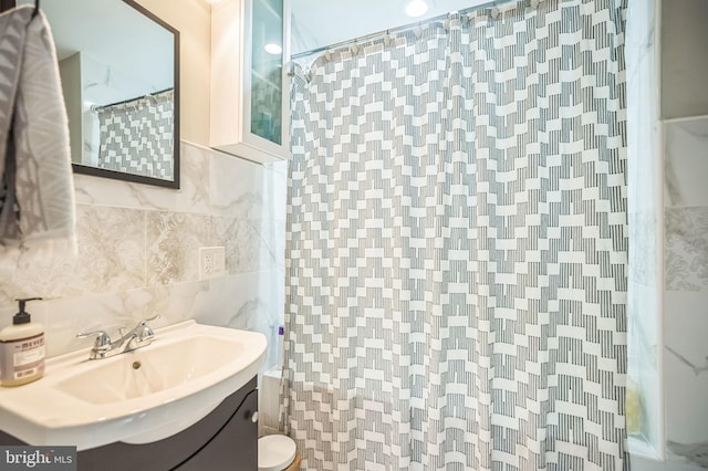 bathroom with curtained shower, vanity, tile walls, and toilet