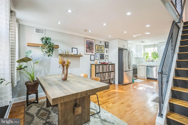 dining area with sink, light hardwood / wood-style floors, and ornamental molding