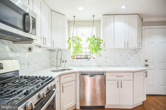 kitchen featuring tasteful backsplash, ornamental molding, stainless steel appliances, sink, and white cabinets