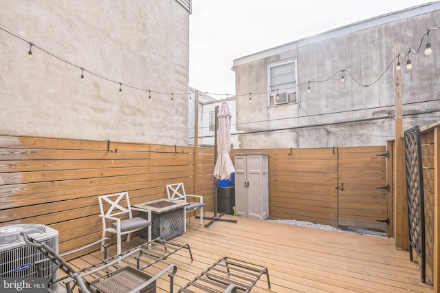 deck with central AC unit and an outdoor fire pit