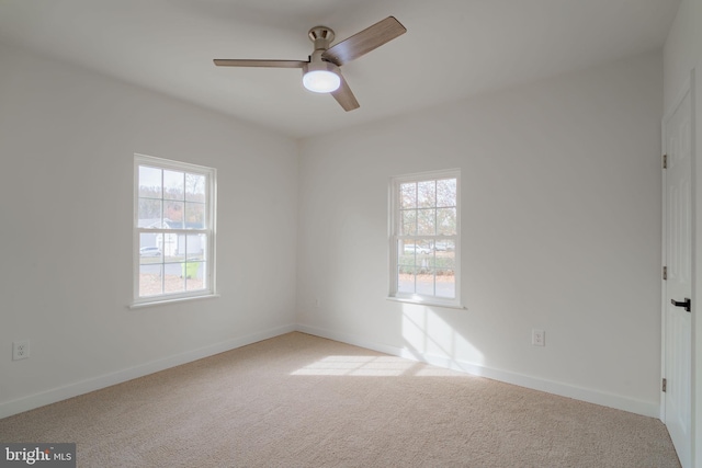 empty room with ceiling fan, a healthy amount of sunlight, and light colored carpet