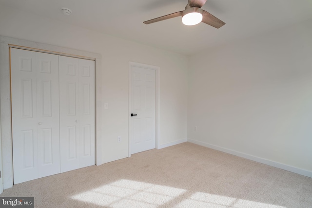 unfurnished bedroom featuring ceiling fan, a closet, and light colored carpet