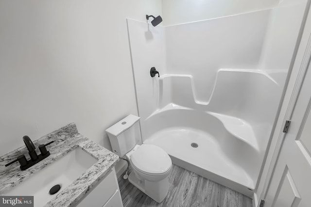 bathroom with hardwood / wood-style floors, vanity, toilet, and walk in shower