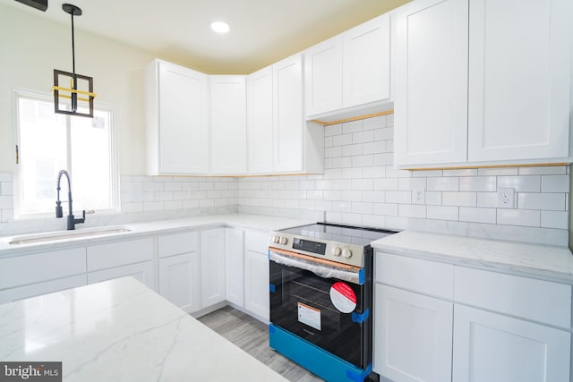 kitchen featuring electric stove, light stone countertops, sink, and white cabinets