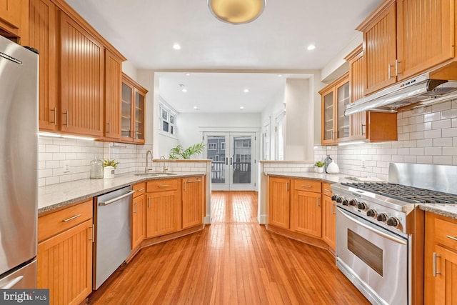 kitchen featuring light stone countertops, tasteful backsplash, sink, light hardwood / wood-style flooring, and stainless steel appliances