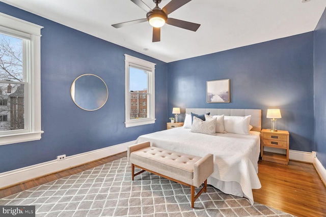 bedroom featuring ceiling fan, multiple windows, and hardwood / wood-style flooring