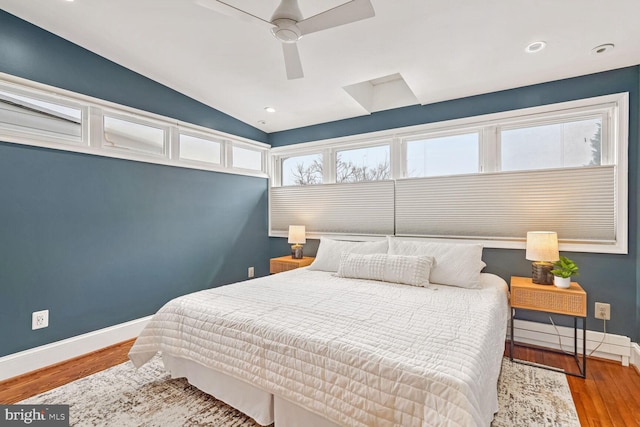 bedroom with ceiling fan, hardwood / wood-style floors, and vaulted ceiling