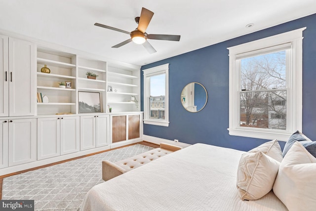 bedroom featuring ceiling fan, multiple windows, and light hardwood / wood-style flooring