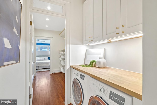 clothes washing area featuring dark hardwood / wood-style floors, cabinets, and washer and dryer