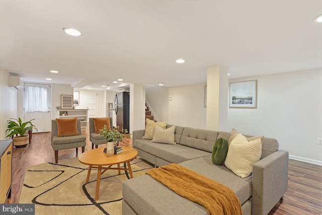 living room with an AC wall unit and hardwood / wood-style floors