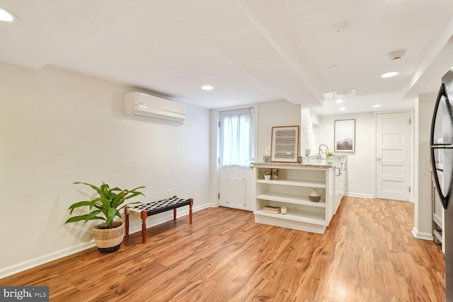 kitchen with a wall mounted air conditioner, light hardwood / wood-style flooring, and light stone countertops