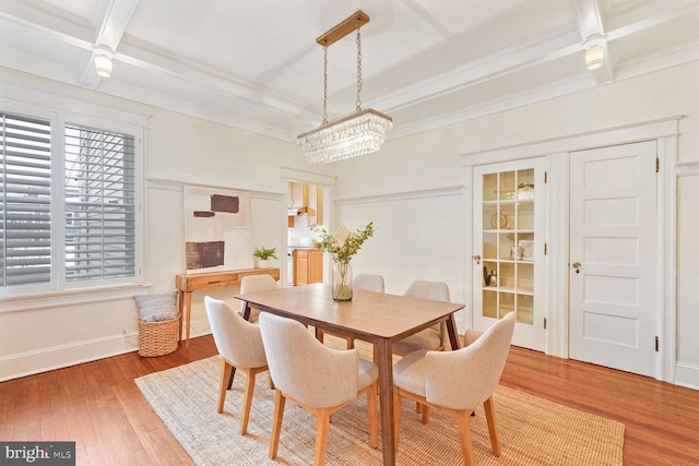 dining area featuring hardwood / wood-style floors, ornamental molding, beam ceiling, and an inviting chandelier