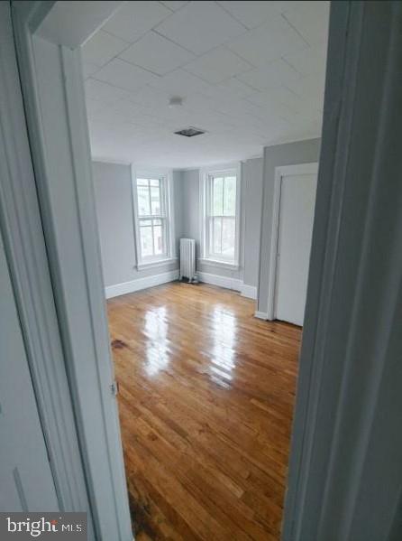 empty room with wood-type flooring and radiator heating unit