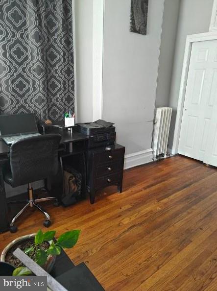 office with hardwood / wood-style floors and radiator heating unit