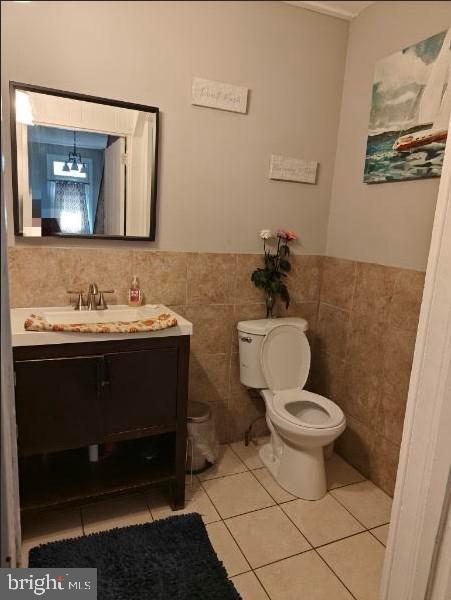 bathroom featuring tile patterned flooring, vanity, tile walls, and toilet