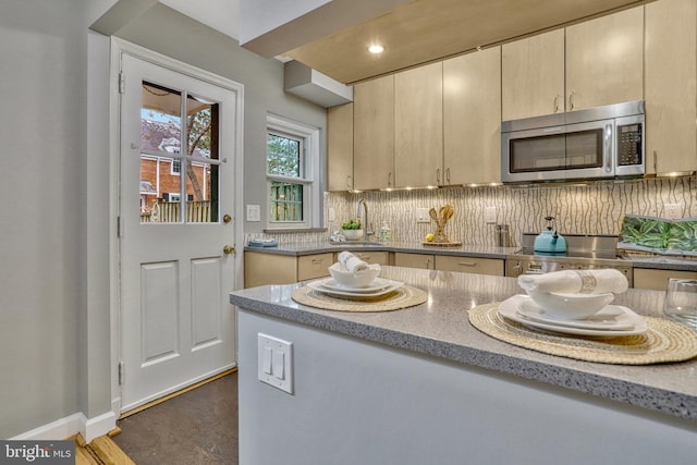 kitchen with range, light stone countertops, sink, and backsplash