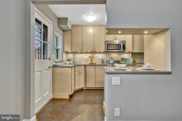 kitchen featuring cream cabinetry, kitchen peninsula, sink, and backsplash