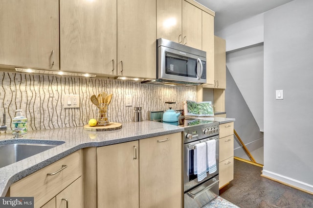 kitchen with appliances with stainless steel finishes, light stone counters, light brown cabinetry, and decorative backsplash