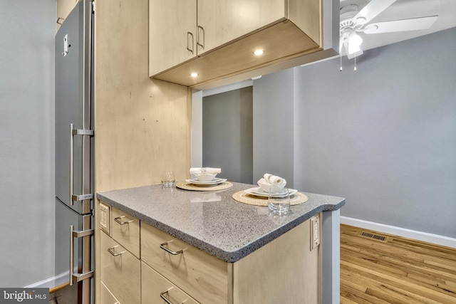 kitchen featuring ceiling fan, high end fridge, light brown cabinets, and light wood-type flooring