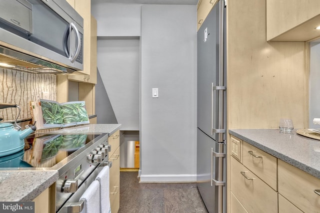 kitchen with light stone counters, light brown cabinetry, tasteful backsplash, and appliances with stainless steel finishes