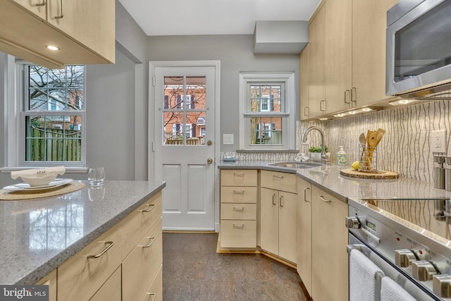 kitchen featuring stainless steel appliances, sink, light brown cabinets, and light stone counters