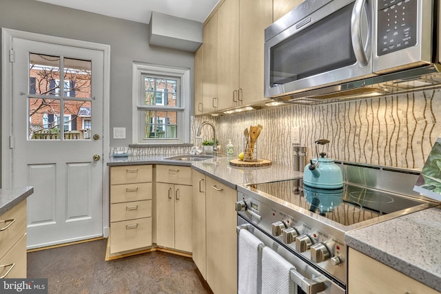 kitchen featuring appliances with stainless steel finishes, light brown cabinetry, sink, backsplash, and light stone counters