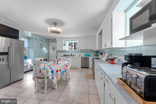 kitchen with decorative backsplash, sink, white cabinets, and stainless steel appliances